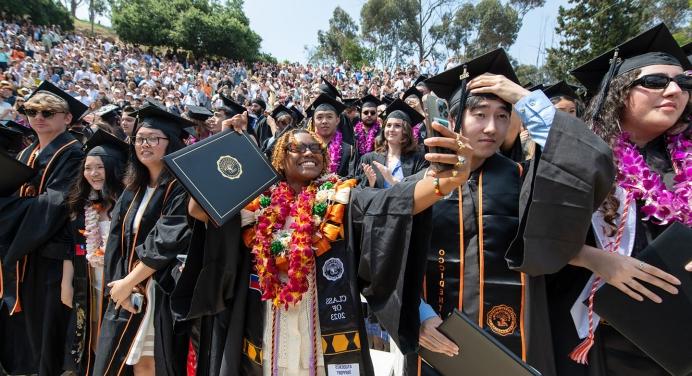 Proud graduates holding up their degrees on Commencement Day