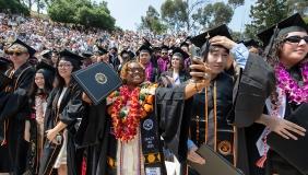 Proud graduates holding up their degrees on Commencement Day